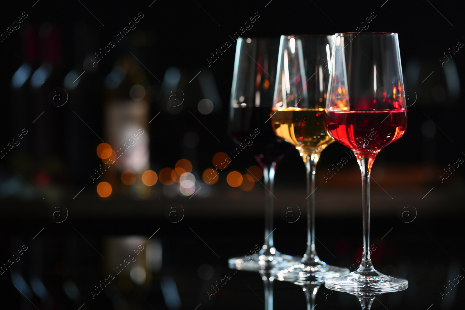 Photo of Row of glasses with different wines on bar counter against blurred background. Space for text