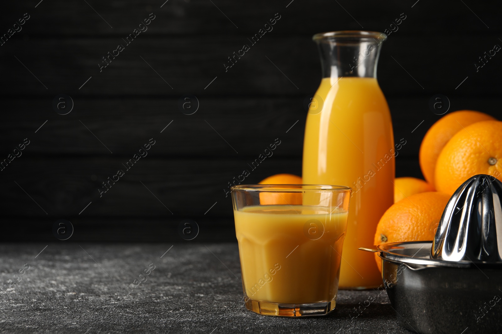 Photo of Tasty fresh oranges and juice on black table, closeup. Space for text