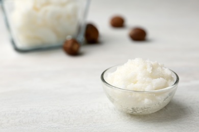 Photo of Shea butter in bowl and nuts on table