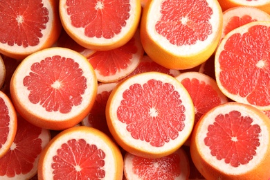 Many sliced fresh grapefruits as background, top view