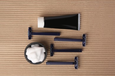 Different men's shaving accessories on brown corrugated cardboard, flat lay