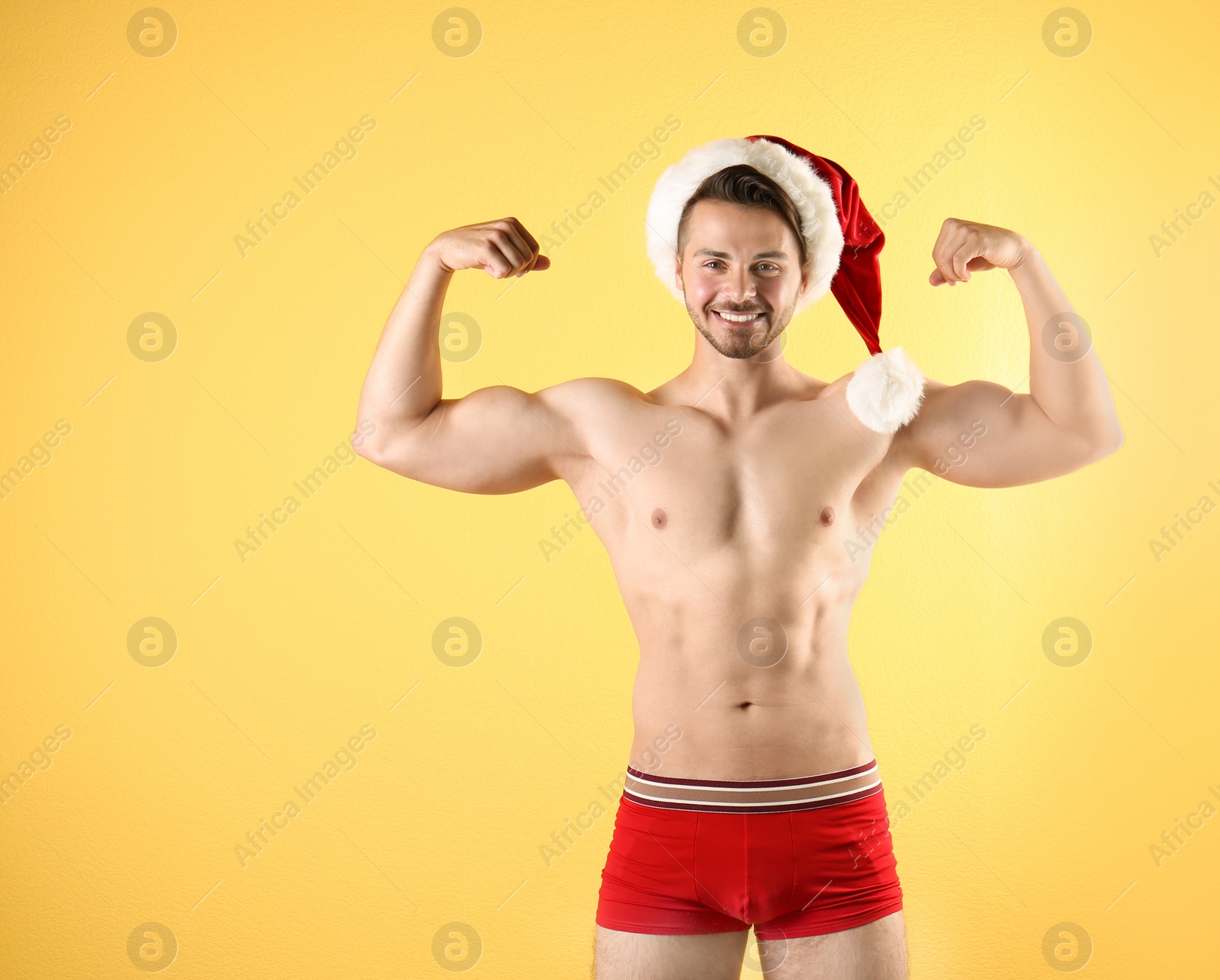 Photo of Shirtless young Santa Claus with sexy body on color background