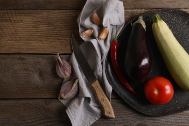 Photo of Cooking ratatouille. Vegetables and knife on wooden table, flat lay. Space for text