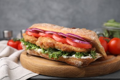 Photo of Delicious sandwich with schnitzel on grey wooden table