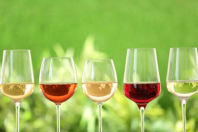 Photo of Row of glasses with different wines against blurred background