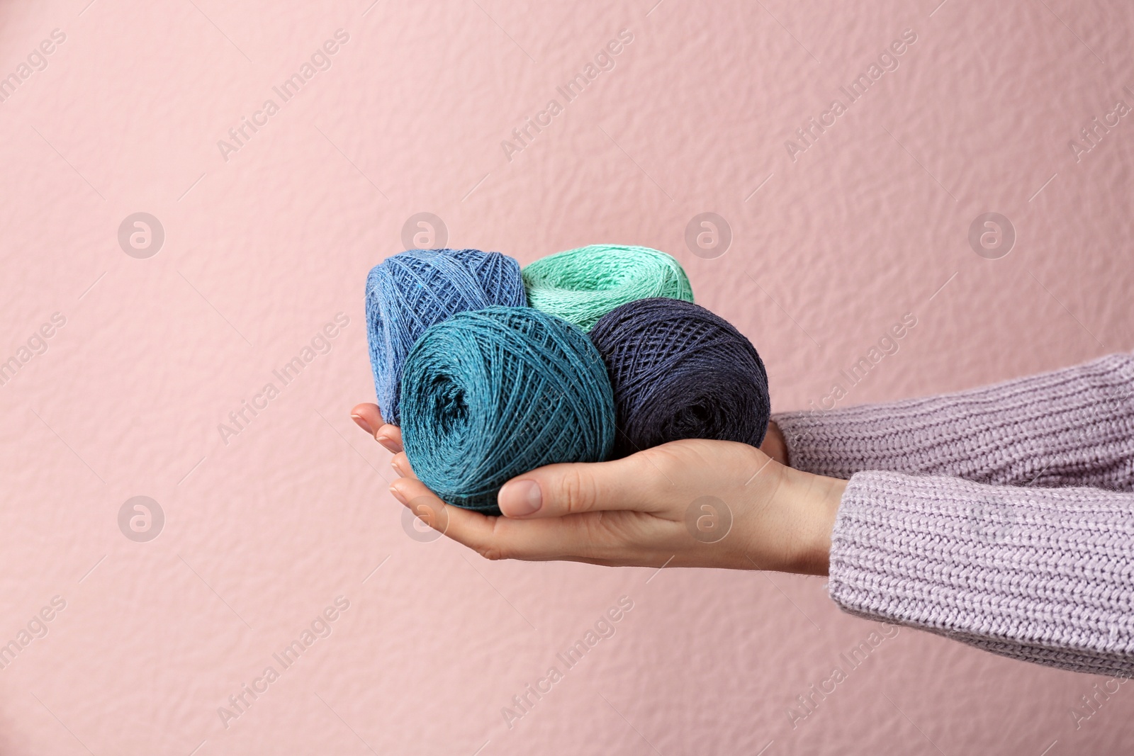 Photo of Woman holding clews of threads against color background, closeup