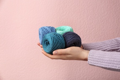 Woman holding clews of threads against color background, closeup