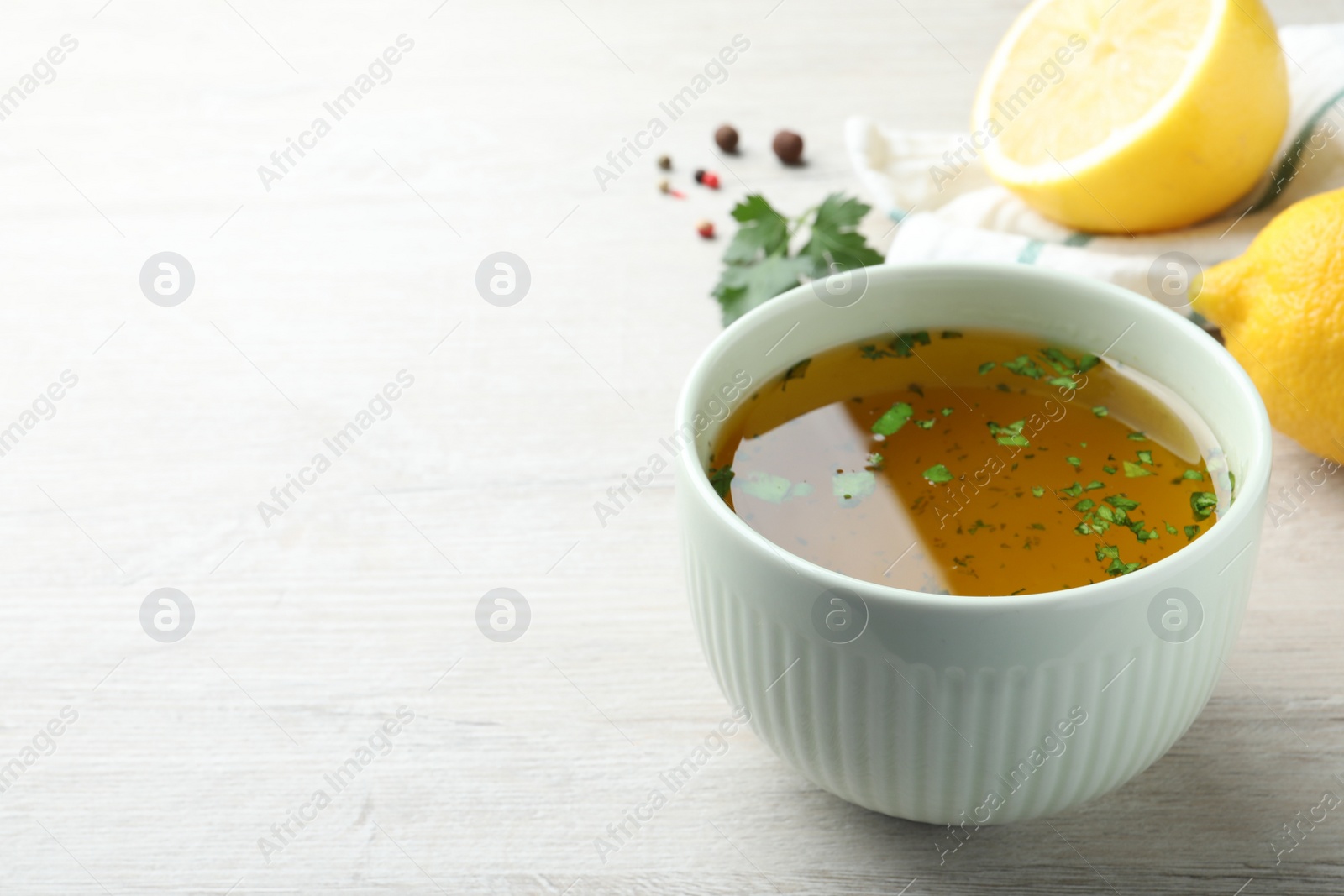 Photo of Bowl with lemon sauce on white wooden table, space for text. Delicious salad dressing