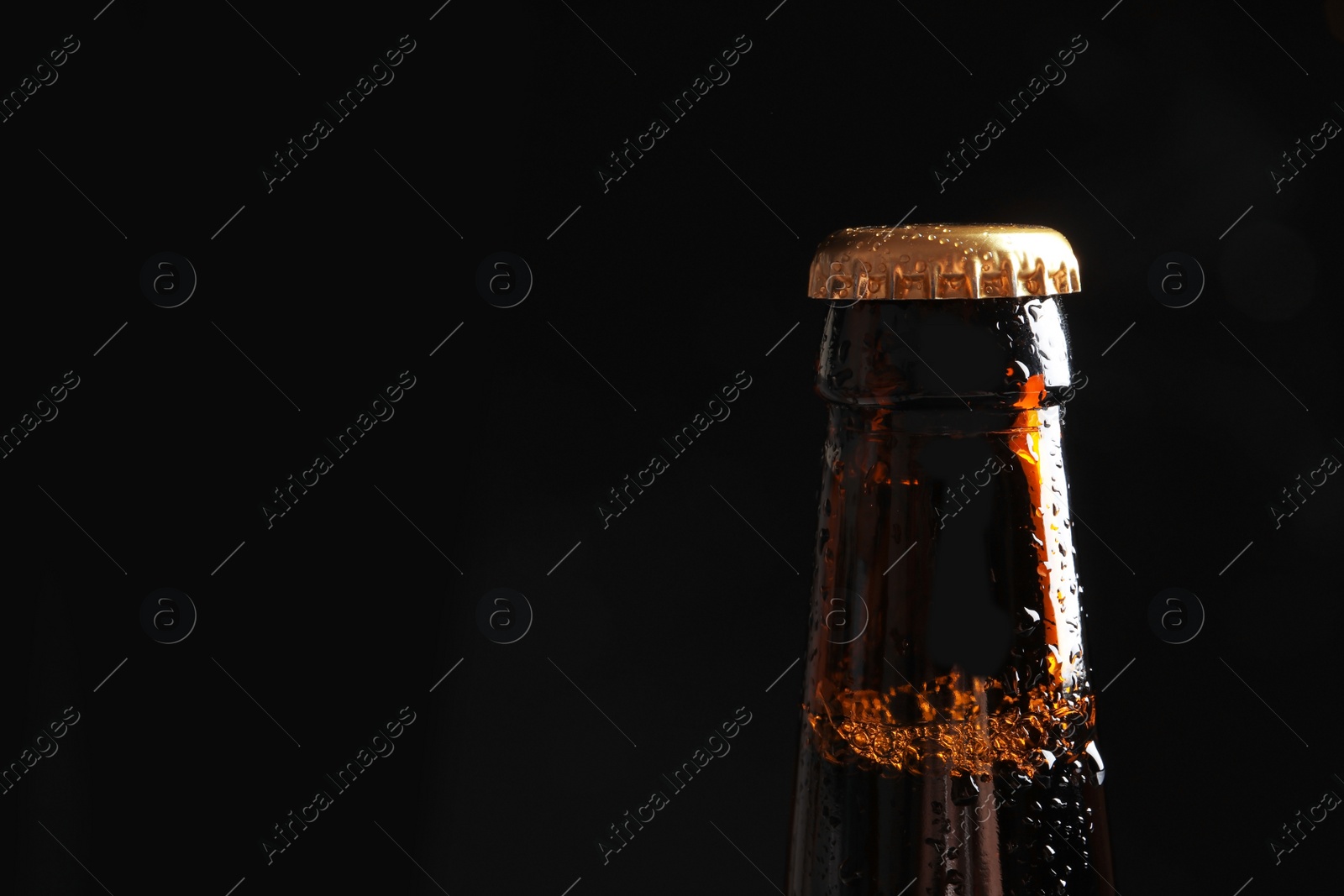 Photo of Bottle of tasty cold beer on black background, closeup