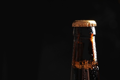 Photo of Bottle of tasty cold beer on black background, closeup