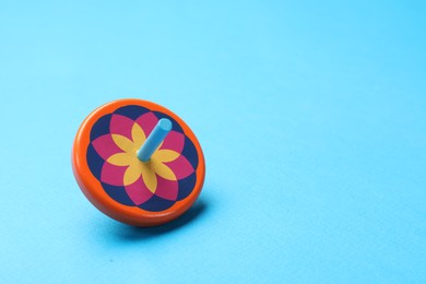 Photo of One colorful spinning top on light blue background, space for text