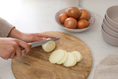 Photo of Woman cutting white onion into rings at countertop, closeup