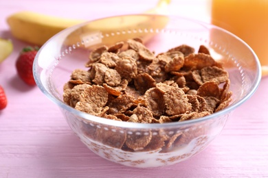 Photo of Cornflakes on pink wooden table, closeup. Healthy breakfast