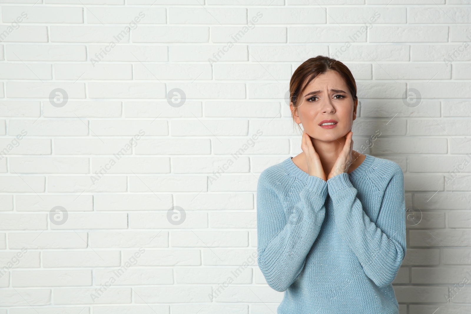 Photo of Woman suffering from cough near brick wall. Space for text