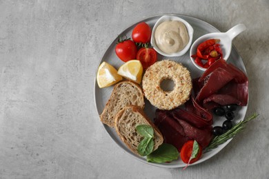 Photo of Delicious bresaola and other ingredients for sandwich on light table, top view. Space for text