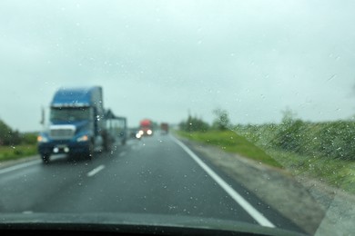 Photo of Blurred view of country road through wet car window. Rainy weather