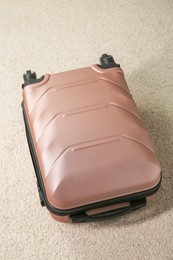 Photo of Stylish suitcase packed for travel on beige rug