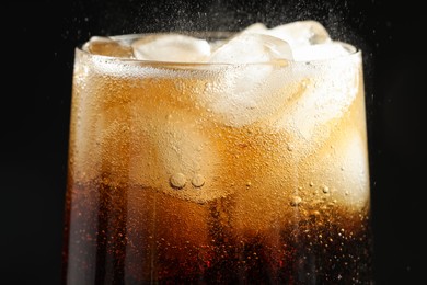 Photo of Glass of refreshing soda drink with ice cubes on black background, closeup