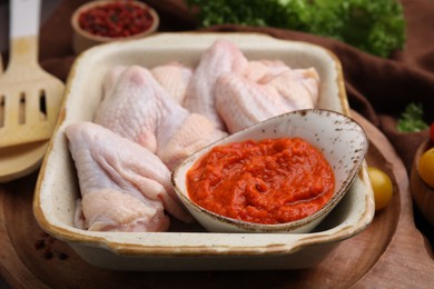 Photo of Fresh marinade and raw chicken on table, closeup