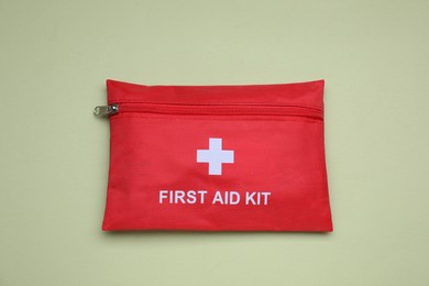 Photo of First aid kit on light green background, top view