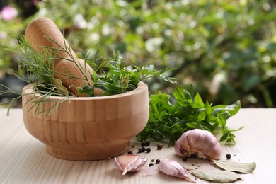 Photo of Mortar with pestle and different ingredients on wooden table outdoors