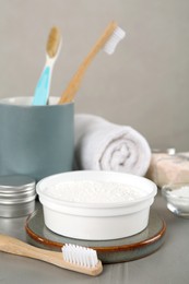 Photo of Composition with tooth powder and brushes on grey table