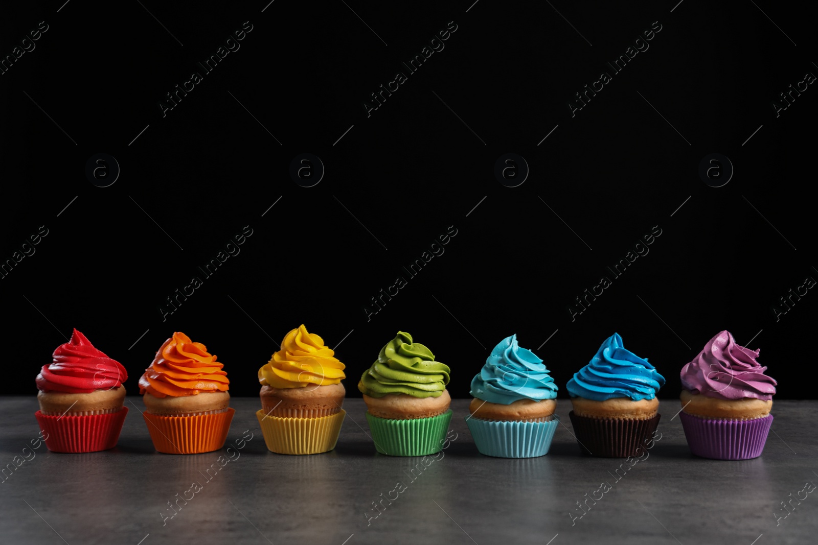 Photo of Delicious birthday cupcake on table against black background