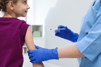 Photo of Doctor giving injection to little girl in hospital, closeup. Immunization concept