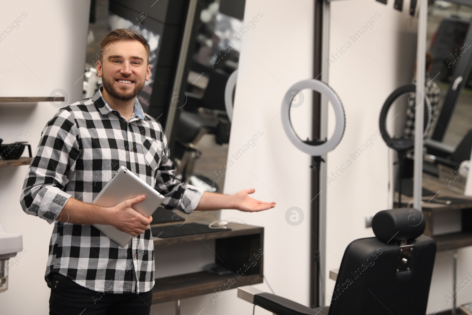 Photo of Young business owner with tablet in barber shop