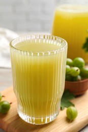Photo of Tasty gooseberry juice and fresh berries on wooden board, closeup