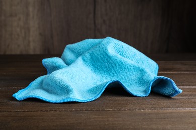 Photo of Light blue microfiber cloth on wooden table, closeup