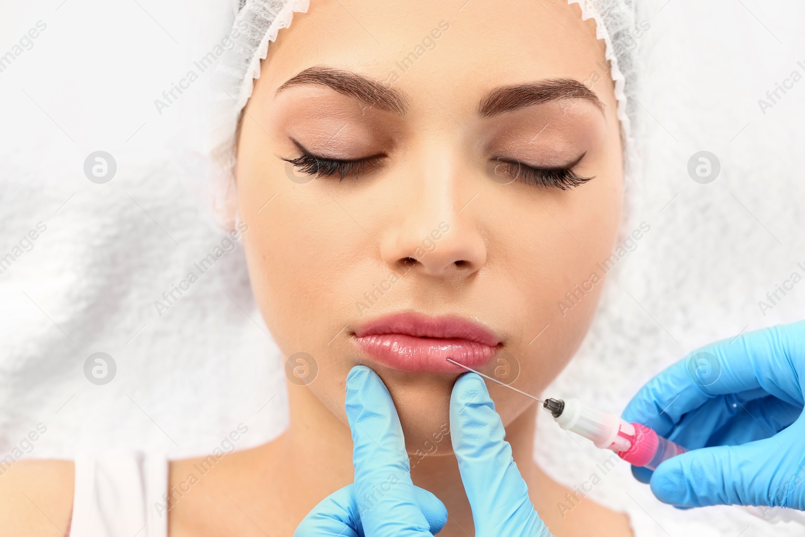 Photo of Young woman getting lip injection in beautician salon, closeup