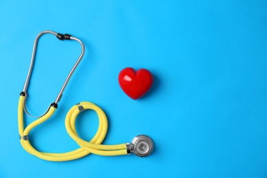 Photo of Stethoscope and heart model on color background, top view. Medical equipment