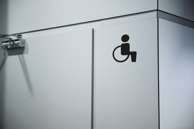 Image of Special needs accessible public toilet sign on white wall. Wheelchair symbol