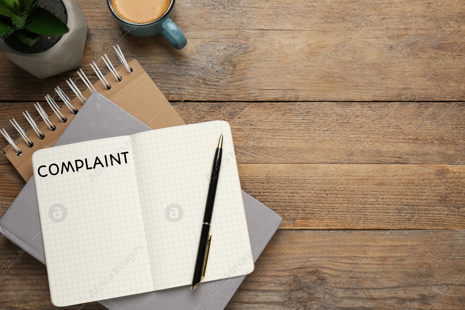 Image of Notebook with word Complaint and cup of coffee on wooden table, flat lay. Space for text