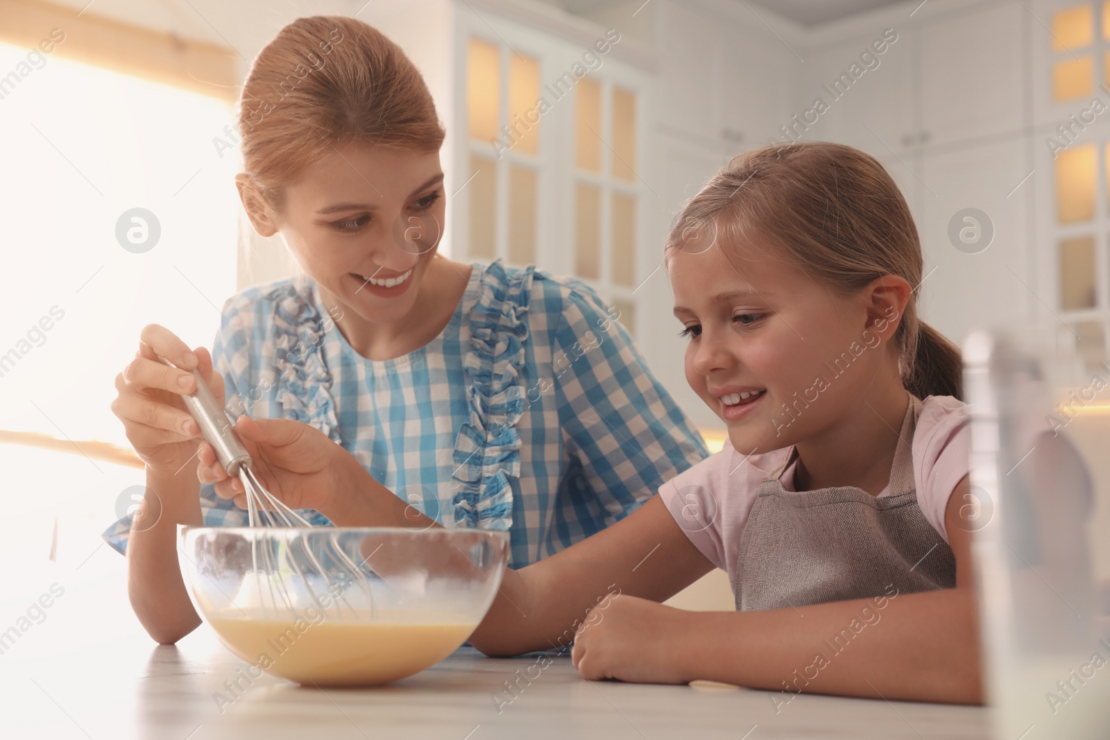 Photo of Mother and daughter making dough together in kitchen