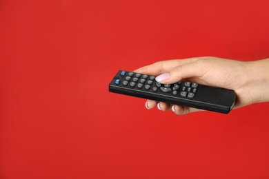 Photo of Woman holding remote control on red background, closeup