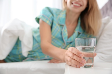 Photo of Woman with glass of clean water lying in bed at home, closeup