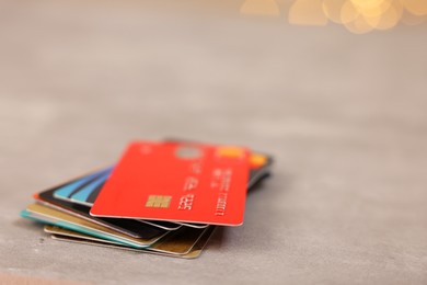 Photo of Pile of different credit cards on grey table, closeup. Space for text