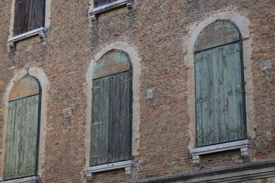 Exterior of old brick building with closed wooden shutters on windows