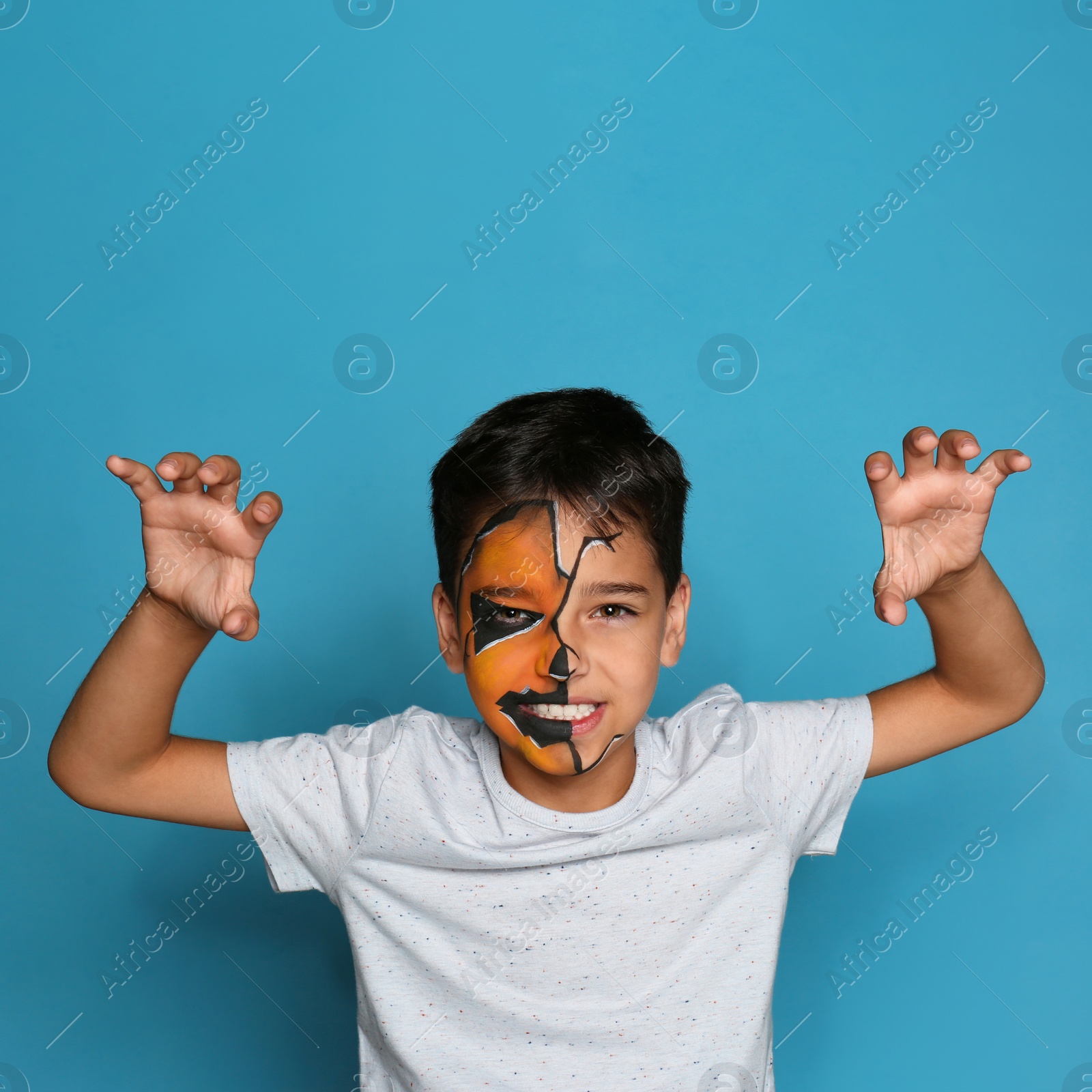 Photo of Cute little boy with face painting on blue background