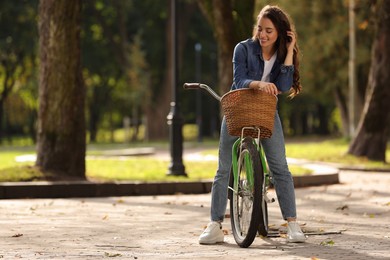 Photo of Young woman with bicycle in park, space for text