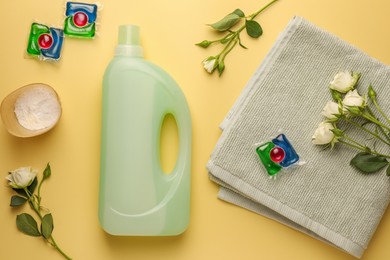 Photo of Flat lay composition with bottles of fabric softener on pale yellow background