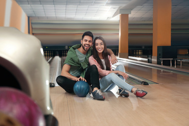 Photo of Happy young couple with ball in bowling club