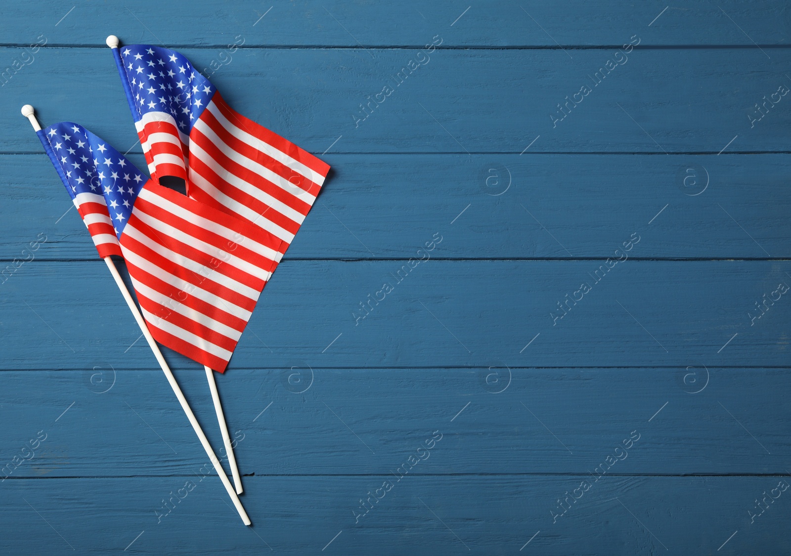 Photo of American flags on blue wooden table, flat lay with space for text. Memorial Day