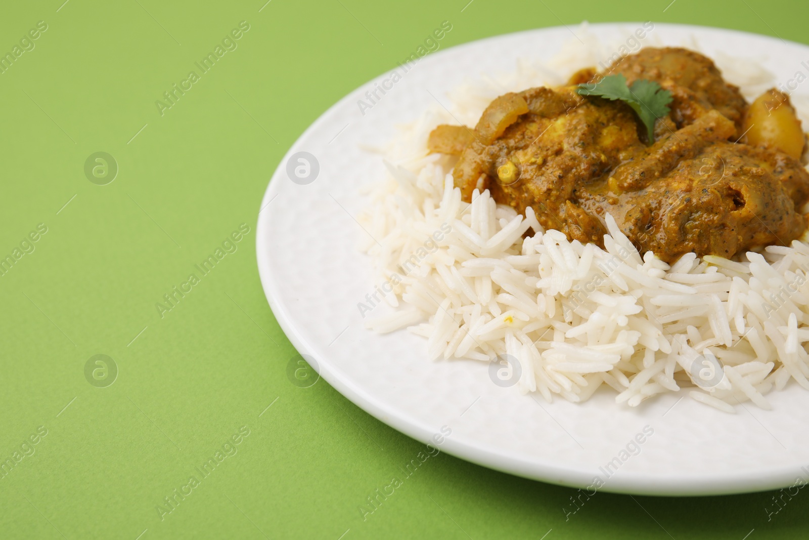 Photo of Delicious chicken curry with rice on green background, closeup