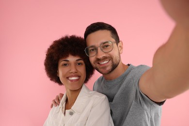 Photo of International dating. Happy couple taking selfie on pink background