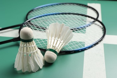 Feather badminton shuttlecocks and rackets on green table, closeup