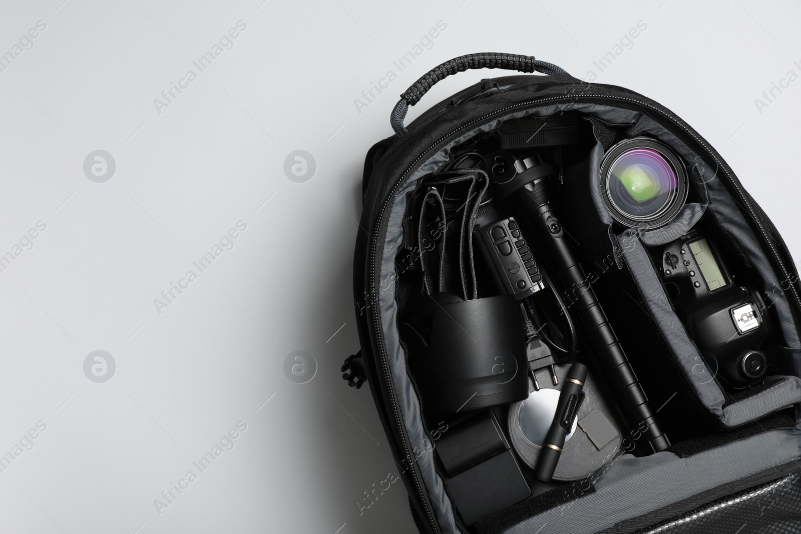 Photo of Professional photography equipment in backpack on grey background, top view. Space for text