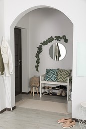 Photo of Hallway interior with stylish furniture and round mirror on light wall